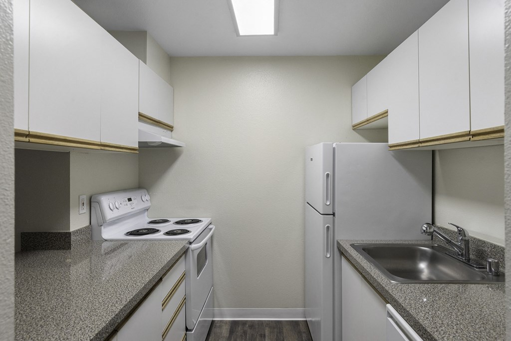 Spacious kitchen with white appliances, white cabinets, and plank flooring at West Mall Place Apartment Homes, Everett