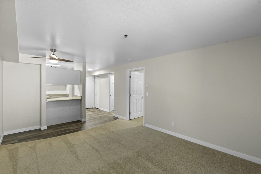 living room with tan carpet and view into kitchen with a ceiling fan at West Mall Place Apartment Homes, Washington, 98208