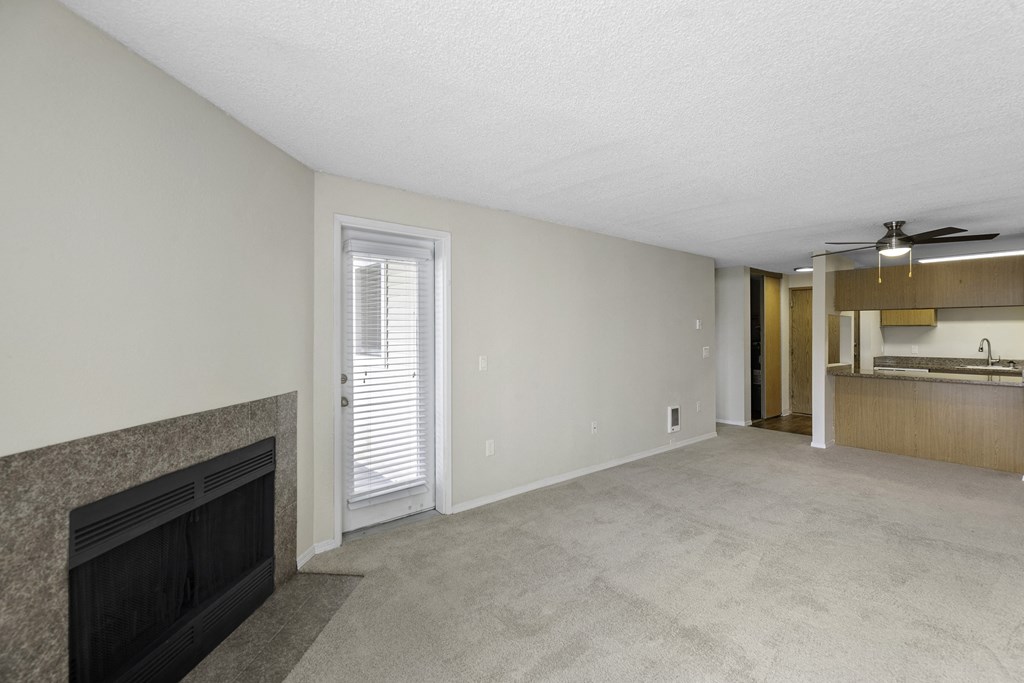 a living room with a fireplace and a kitchen in the background at Willows Court Apartment Homes, WA 98125