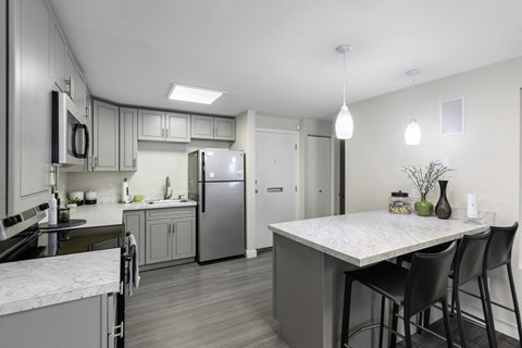 a kitchen with a marble counter top and stainless steel refrigerator