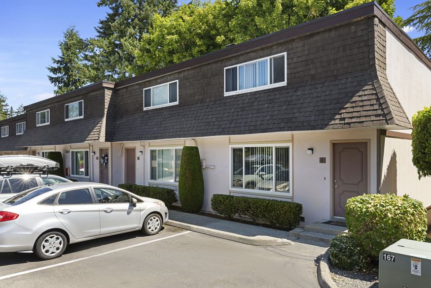 Side View of Townhome Buildings with White Walls, Manicured Shrubs, and Resident Reserved Parking Side View of Townhome Buildings with White Walls, Manicured Shrubs, and Resident Reserved Parking at Woodlake Townhomes, Washington - Photo Gallery