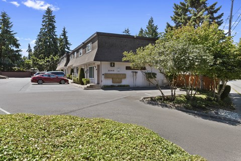 View of the Property Grounds with green shrubs, bushes, and parking area  at Woodlake Townhomes, WA 98026