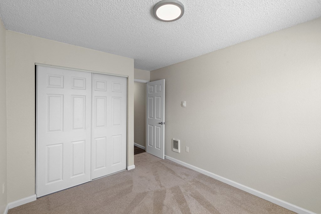 a bedroom with two doors, tan carpeted floor, and overhead lighting  at Park Edmonds Apartment Homes, Washington, 98026
