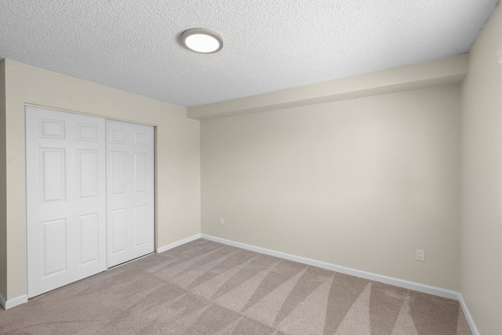a bedroom with a white closet doors and tan carpeting at Park Edmonds Apartment Homes, Edmonds, 98026
