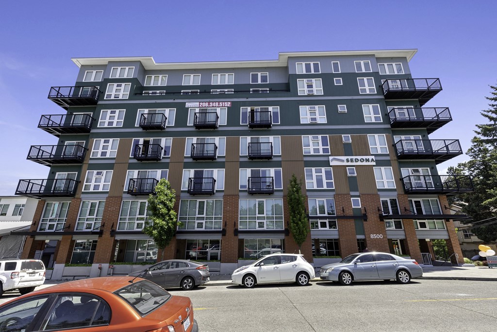 an image of the large property building with cars parked in front of it  at Sedona Apartments, Seattle, WA