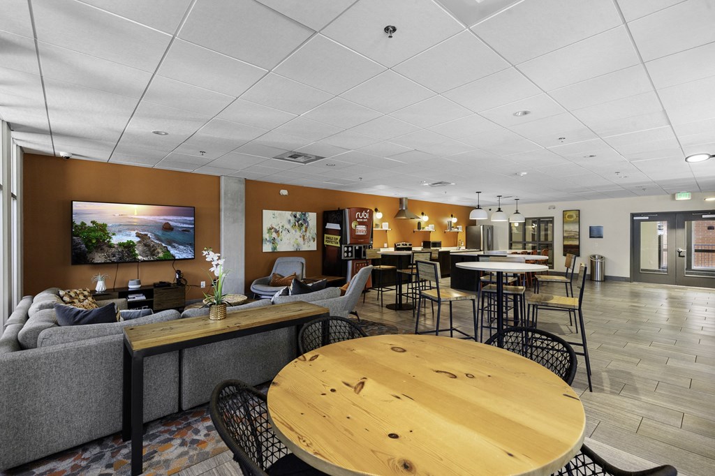 a lounge area with tables and chairs and a resident community kitchen in the background at Sedona Apartments, Seattle, Washington