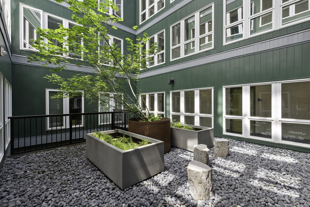 an outdoor courtyard with large concrete planters and stools  t Sedona Apartments, Seattle, 98115