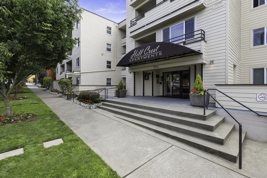 a large white building with a black awning showing property name at Hill Crest Apartment Homes, Seattle, 98126
