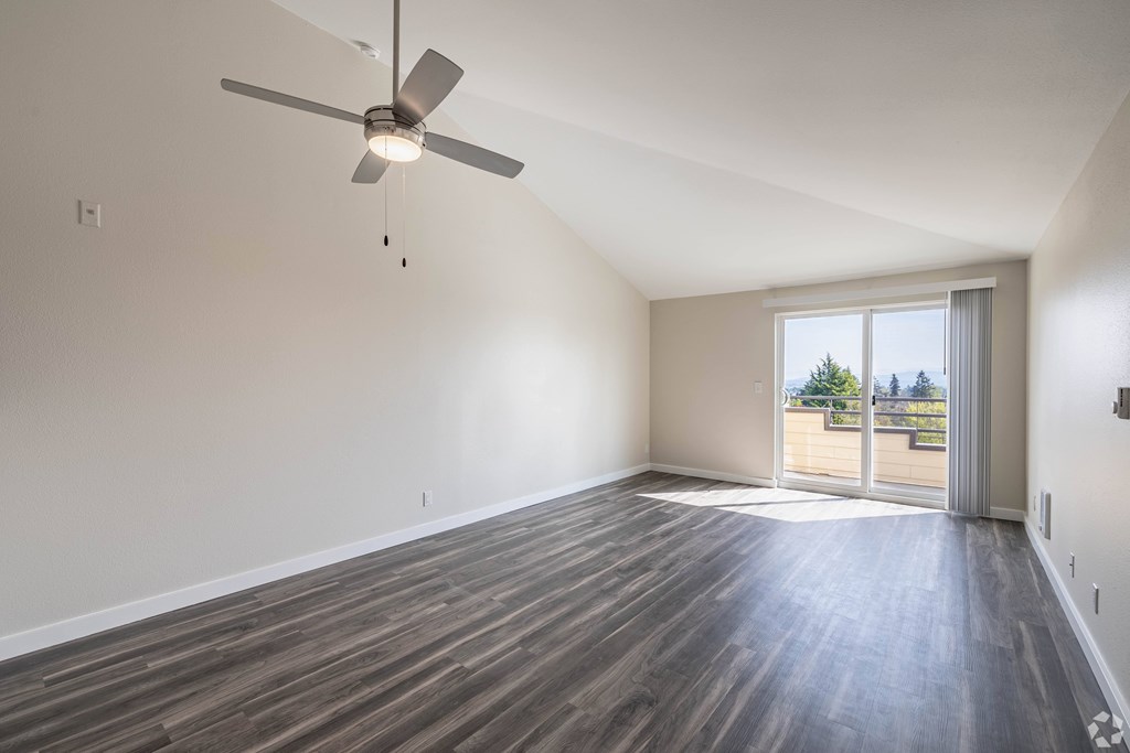 A room with a ceiling fan and sliding glass doors.