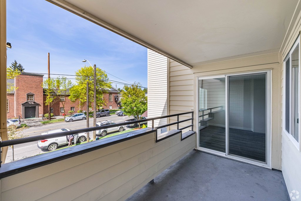 A balcony with a view of a street with cars and houses.