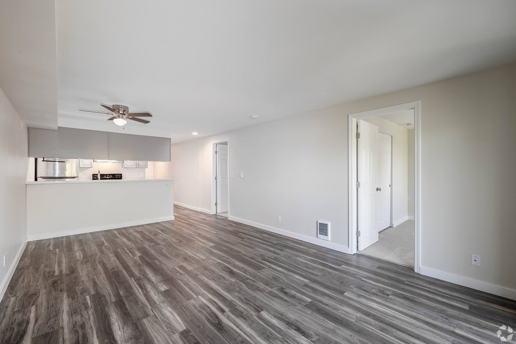 A room with a ceiling fan and wood flooring.