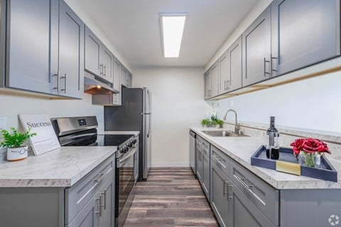 A kitchen with grey cabinets and a white countertop.