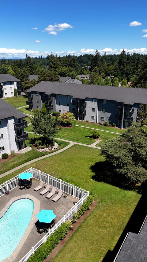 A pool with a hot tub and a white fence in front of a building.