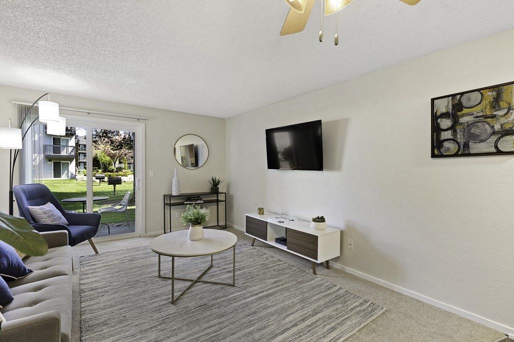 Spacious Living Room with a Couch, Large Sliding Glass Doors and overhead Ceiling Fan at Pacific Park Apartment Homes, Edmonds