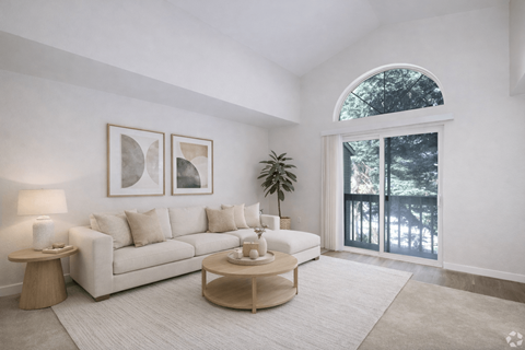 A living room with a white couch, a coffee table, and a potted plant.
