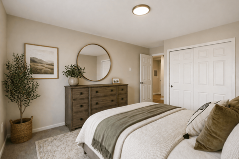 A bedroom with a large bed and a round mirror on the wall.
