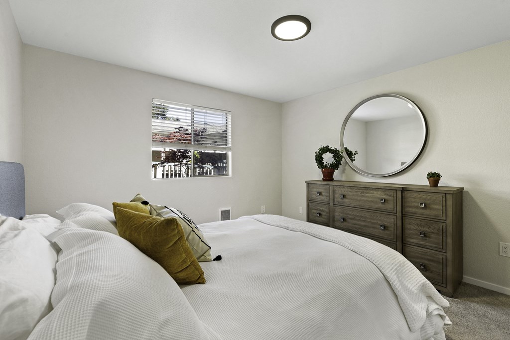 a bedroom with a large bed and a dresser with a mirror