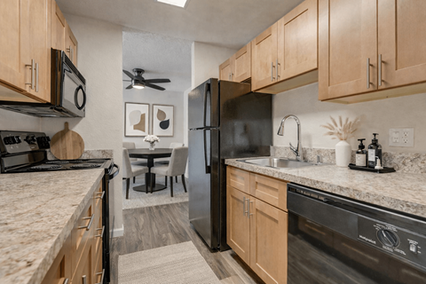 A kitchen with a black refrigerator and wooden cabinets.