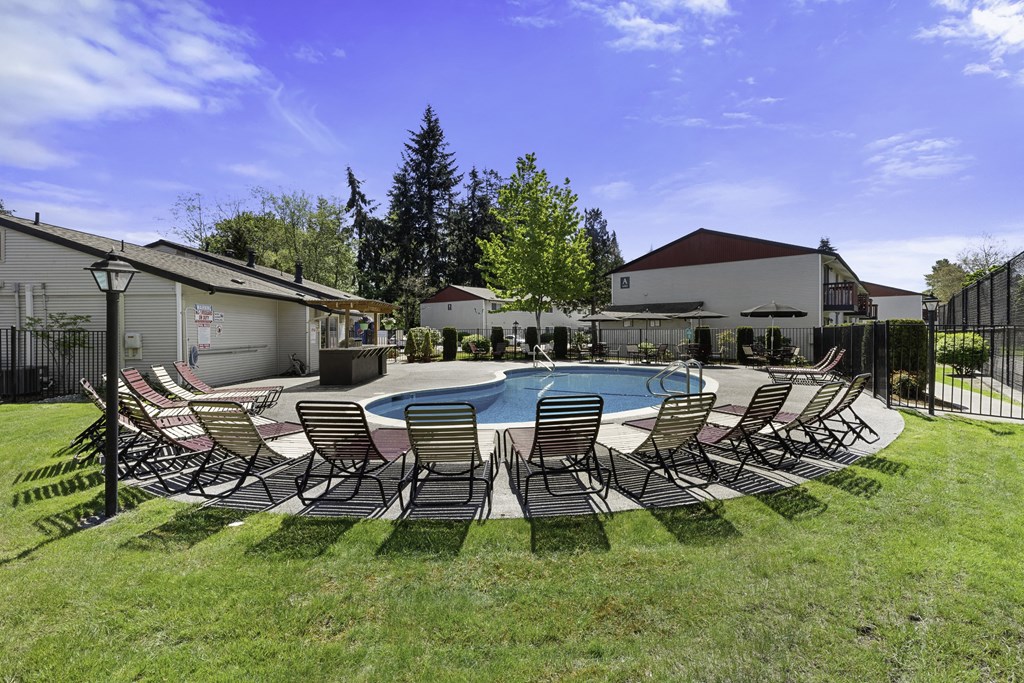 Cool Blue Swimming pool with Lounge Chairs and Grassy Area Cool Blue Swimming pool with Lounge Chairs and Grassy Area at Pinewood Square Apartment Homes, Lynnwood