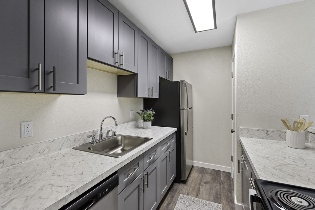 Modern Kitchen with Plank Flooring, Overhead Beam Lighting, and Dark Cabinetry at Pinewood Square Apartment Homes, Washington, 98087