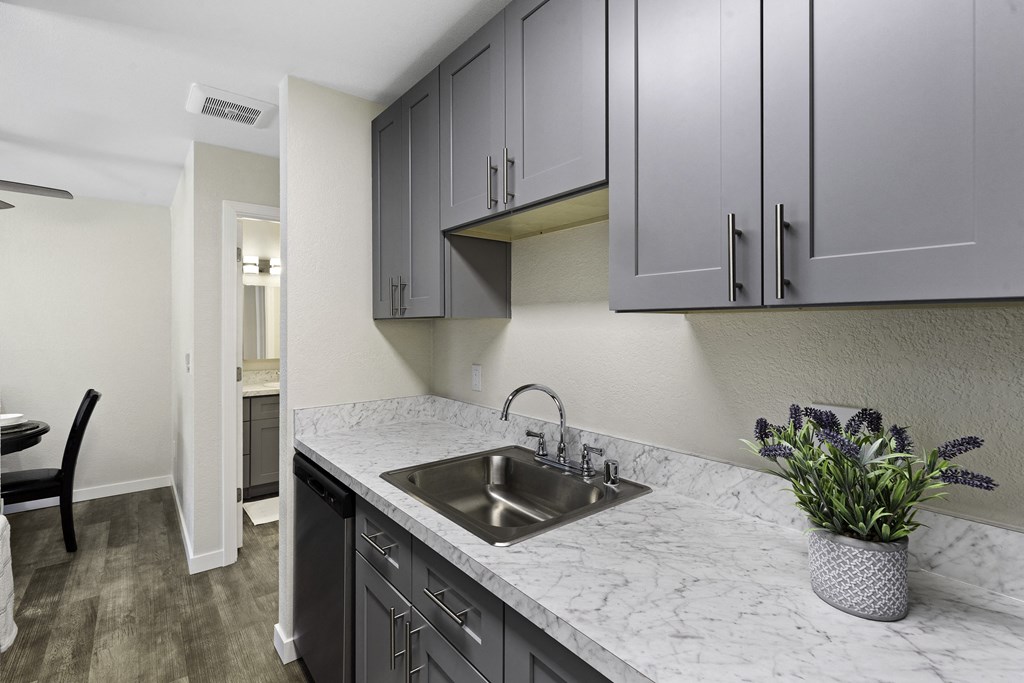 a kitchen with gray cabinets and a stainless steel sink a kitchen with gray cabinets and a stainless steel sink at Pinewood Square Apartment Homes, Washington