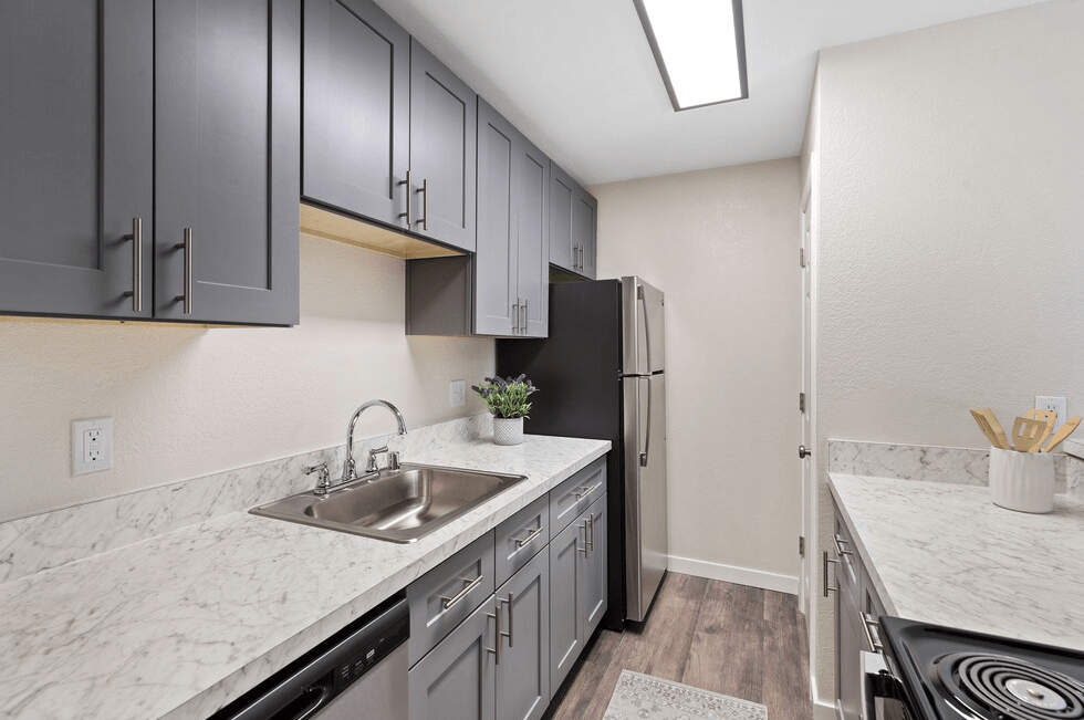 A kitchen with a sink, refrigerator, and cabinets.
