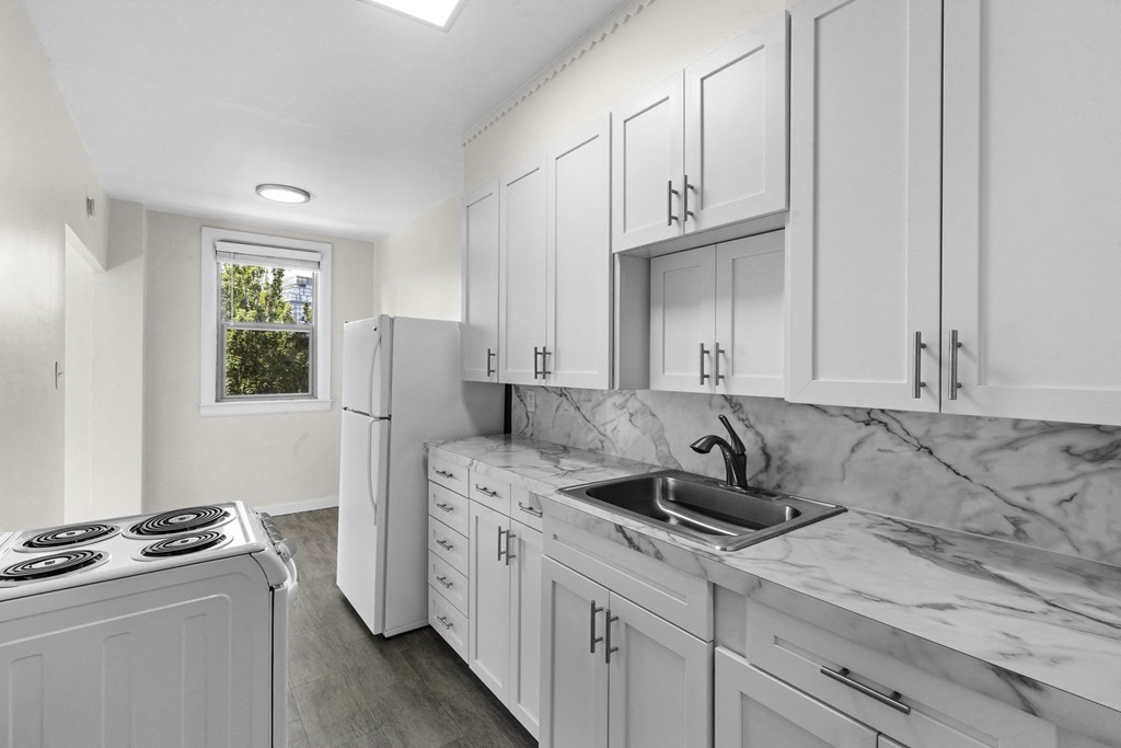 Spacious kitchen with white cabinetry, plank flooring, and marble look countertops at Stockbridge Apartment Homes, Washington