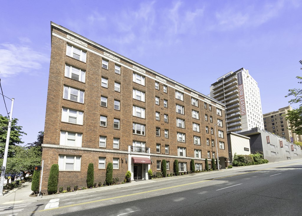 Street view of large brick property building with a street in front of it at Stockbridge Apartment Homes, Seattle, Washington 98101