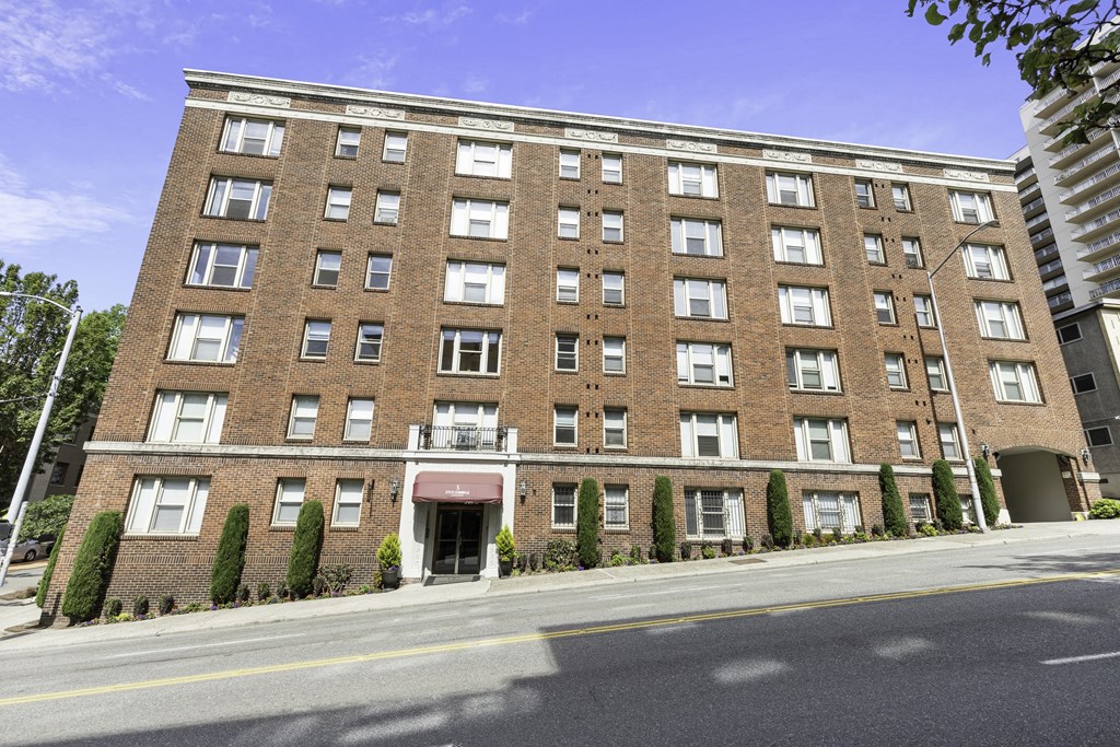 Front Street View of large brick property building with a red awning and a street in front of it at Stockbridge Apartment Homes, Seattle, 98101