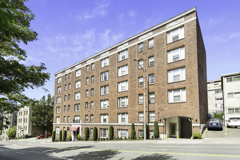 Large brick property building with awning and trees in front of it at Stockbridge Apartment Homes, Seattle