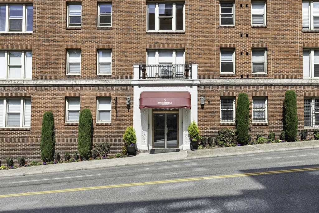 a brick building with a red awning and a street in front of it at Stockbridge Apartment Homes, WA 98101