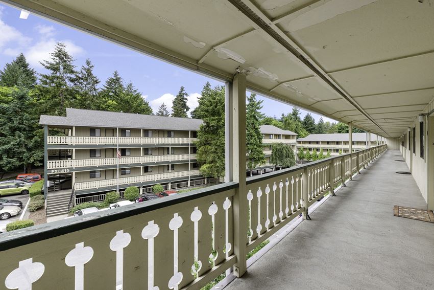a balcony with a white fence and a large building in the background a balcony with a white fence and a large building in the background at Swiss Gables Apartment Homes, Kent, 98032 - Photo Gallery