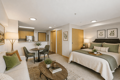 A well-lit bedroom with a bed, couch, and dining table.
