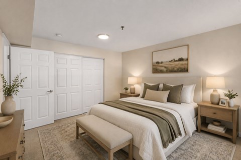 A bedroom with a large bed, a bench, and a painting on the wall.