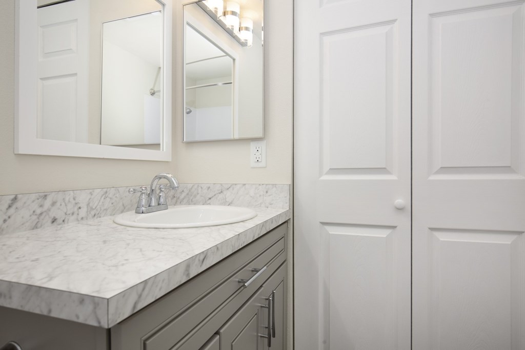 A bathroom with a marble countertop and a white sink.