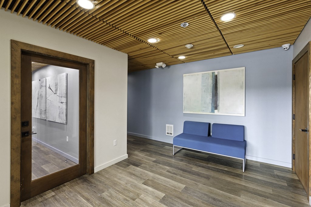 Resident Lobby Area with a blue couch and a large painting on the wall at Excalibur Apartment Homes, Washington, 98004