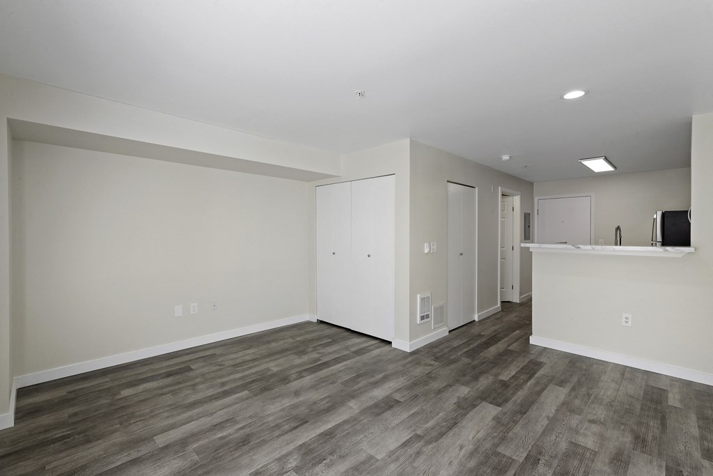 Interior View of a Spacious Living Room with Dark Hardwood Flooring and White Walls at Excalibur Apartment Homes, WA 98004