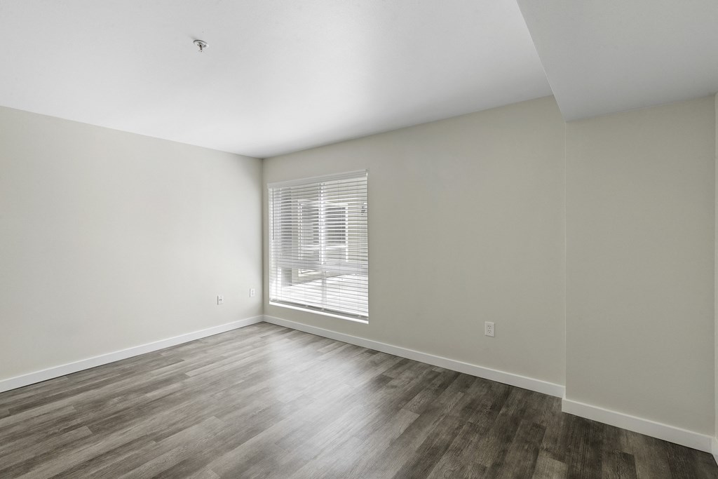 a bedroom with hardwood flooring and a large window at Excalibur Apartment Homes, Bellevue, Washington 98004