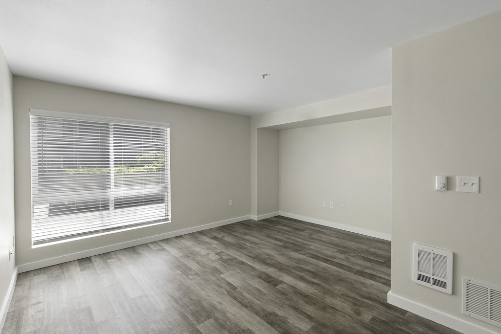 a bedroom with a large window and hardwood floors at Excalibur Apartment Homes, Bellevue, WA