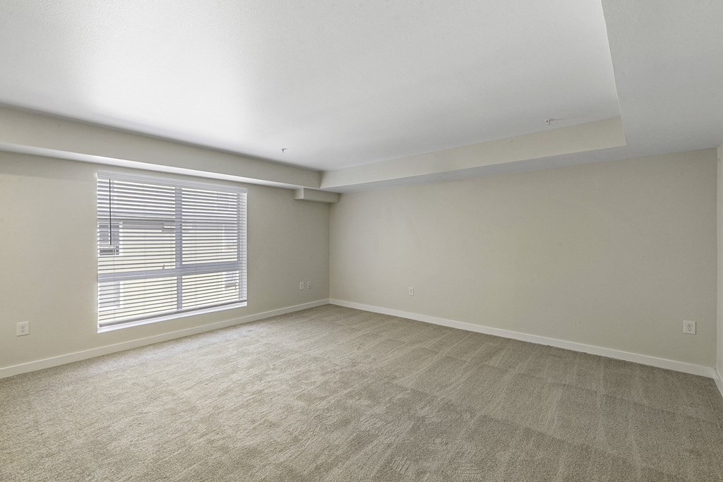 Spacious Living Area with Large, Oversized Windows with Blinds and Tan Plush Carpeting Wall to Wall at Excalibur Apartment Homes, Bellevue, Washington 98004
