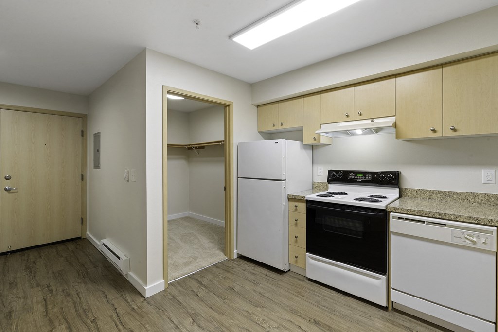 a kitchen with a white refrigerator freezer next to a stove top oven at Excalibur Apartment Homes, Bellevue