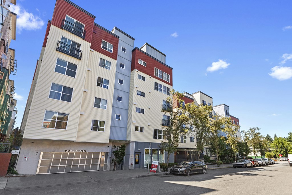 an apartment building with a parking lot in the foreground and a blue sky in the background