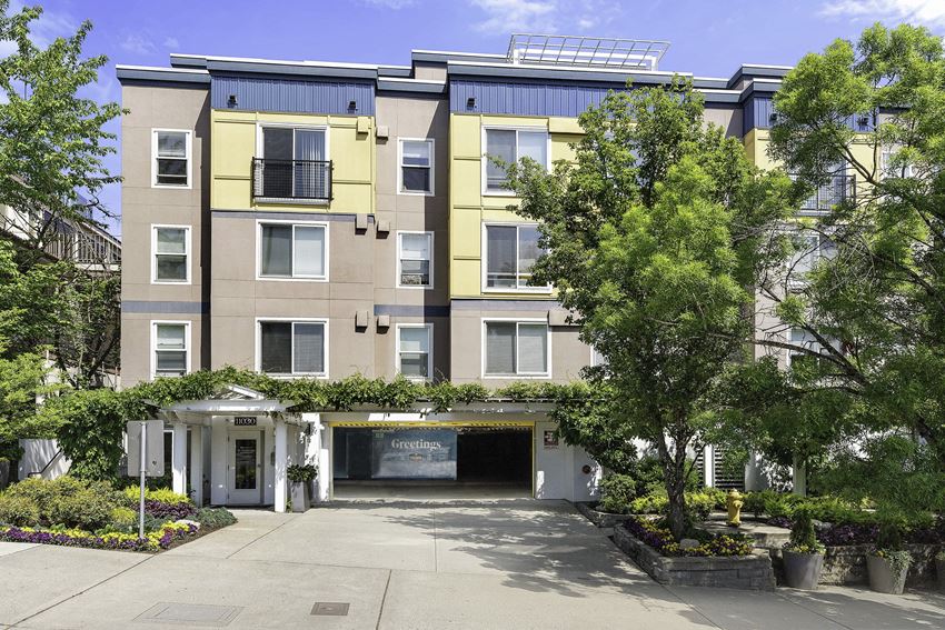 an apartment building with a driveway and trees in front of it an apartment building with a driveway and trees in front of it at Sir Gallahad Apartment Homes, Bellevue, WA - Photo Gallery