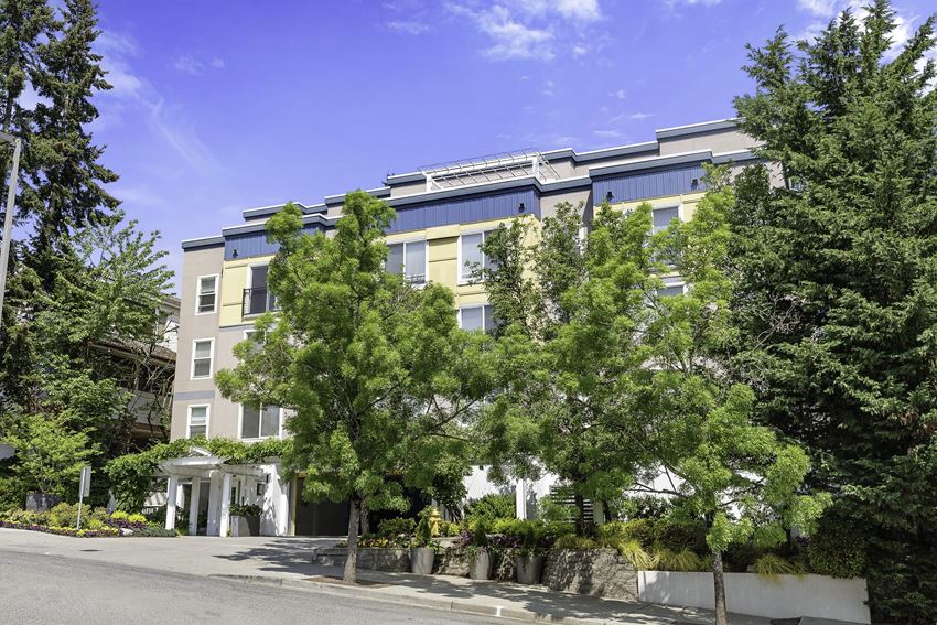 a large apartment building with trees in front of it a large apartment building with trees in front of it at Sir Gallahad Apartment Homes, WA 98004 - Photo Gallery