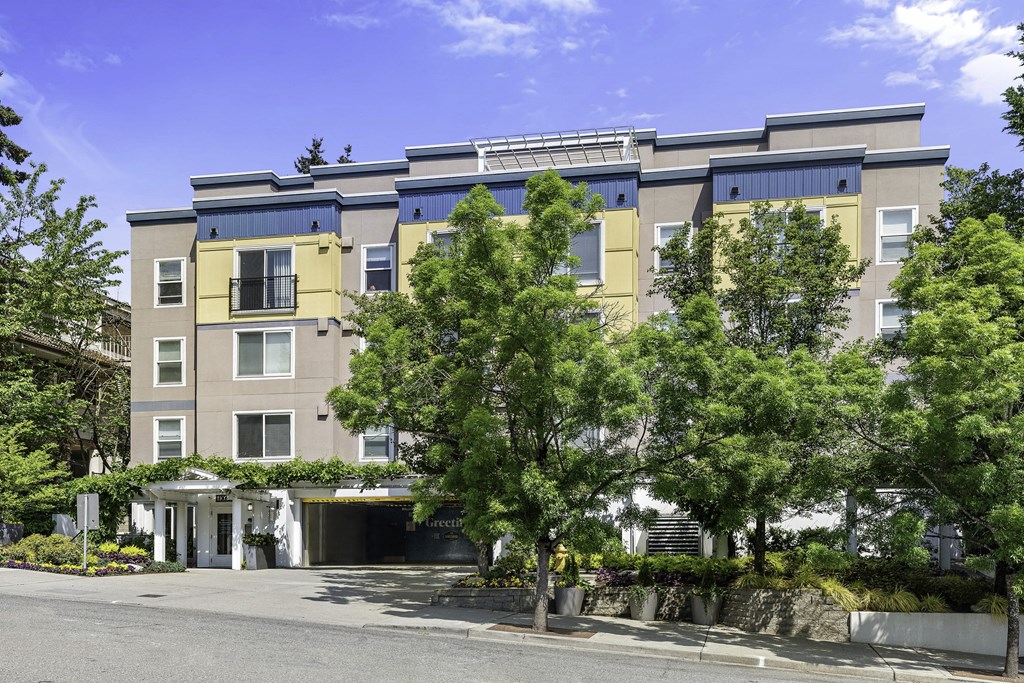 an apartment building with yellow and blue siding and a tree in front of it at Sir Gallahad Apartment Homes, Washington