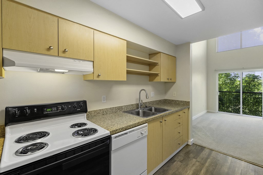 a kitchen with wooden cabinets and a white stove top oven a kitchen with wooden cabinets and a white stove top oven at Sir Gallahad Apartment Homes, Bellevue, 98004