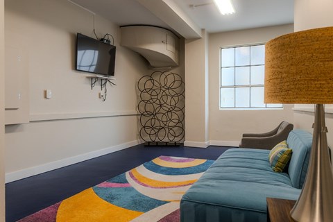 A bedroom with a blue bed and a television on the wall.