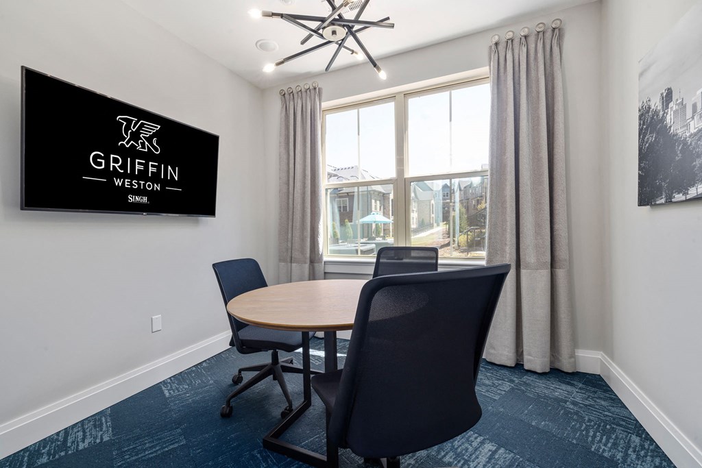 a conference room with a table and chairs and a tv on the wall  at Griffin Weston, Cary, North Carolina