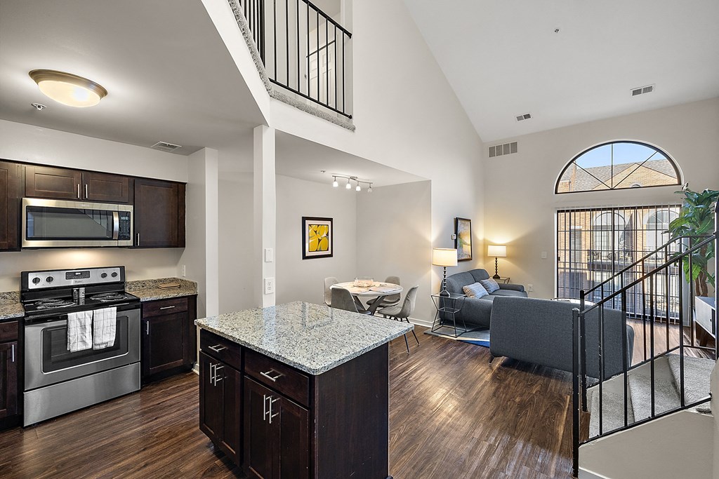 A modern kitchen with dark wood floors and a large island at MainCentre, Northville