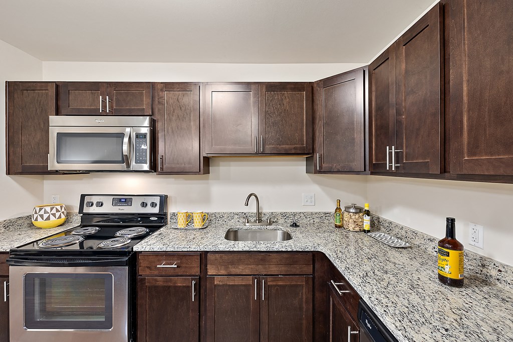 A kitchen with a granite counter top and dark wood cabinets at MainCentre, Northville